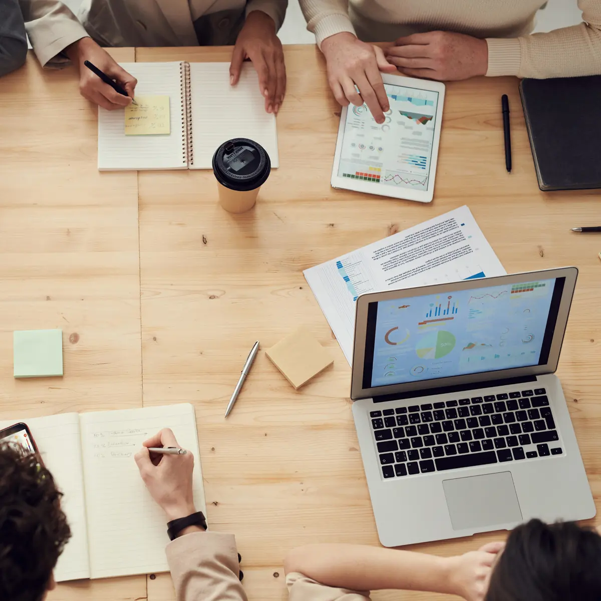 A team planning around a table with laptops and notebooks